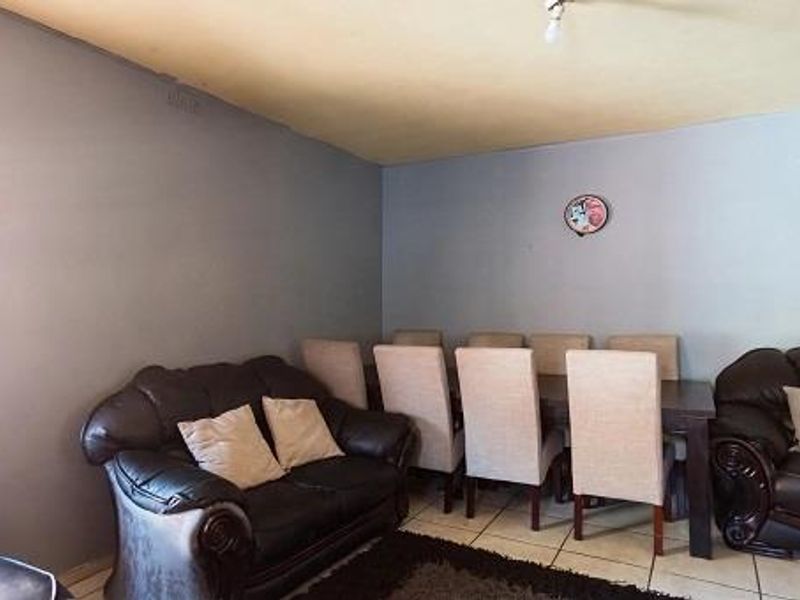 A living area featuring tiled flooring and a window, currently showing signs of wear on the ceiling and walls.