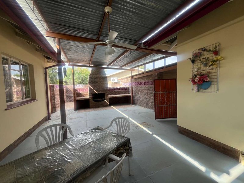 Covered outdoor patio area featuring a built-in brick braai, concrete flooring, and a ceiling fan, ideal for outdoor entertaining.