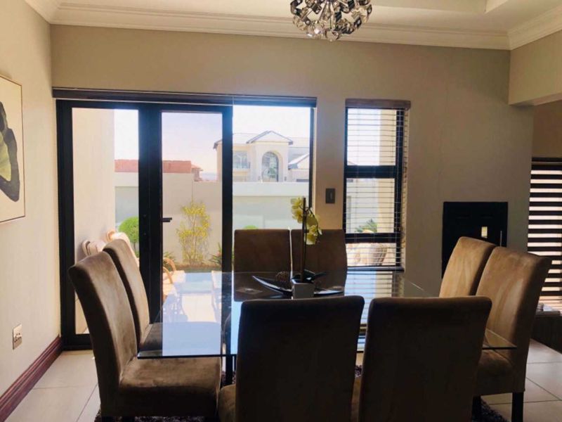 A well-lit dining area featuring tiled flooring, modern sliding glass doors leading to the exterior, and a recessed ceiling detail.