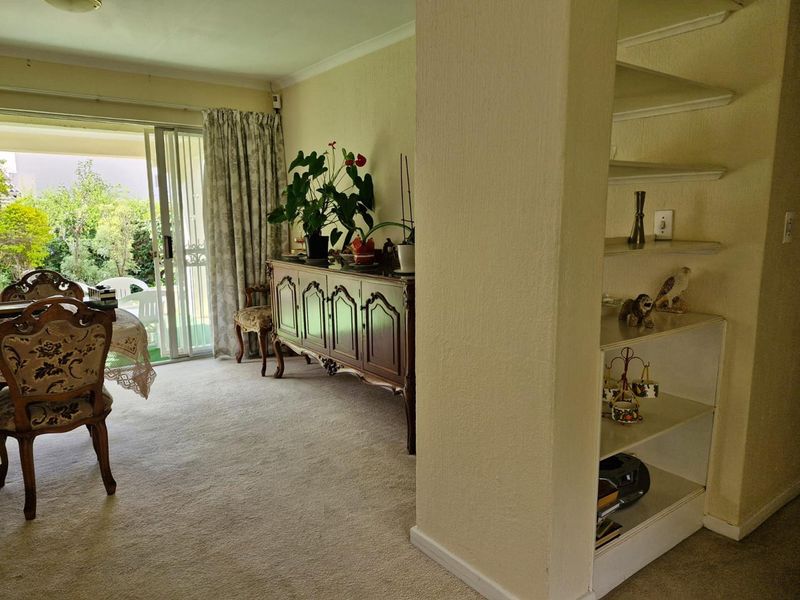 A living area featuring carpeted flooring, built-in shelving, and a sliding glass door providing access to the outdoor patio area.