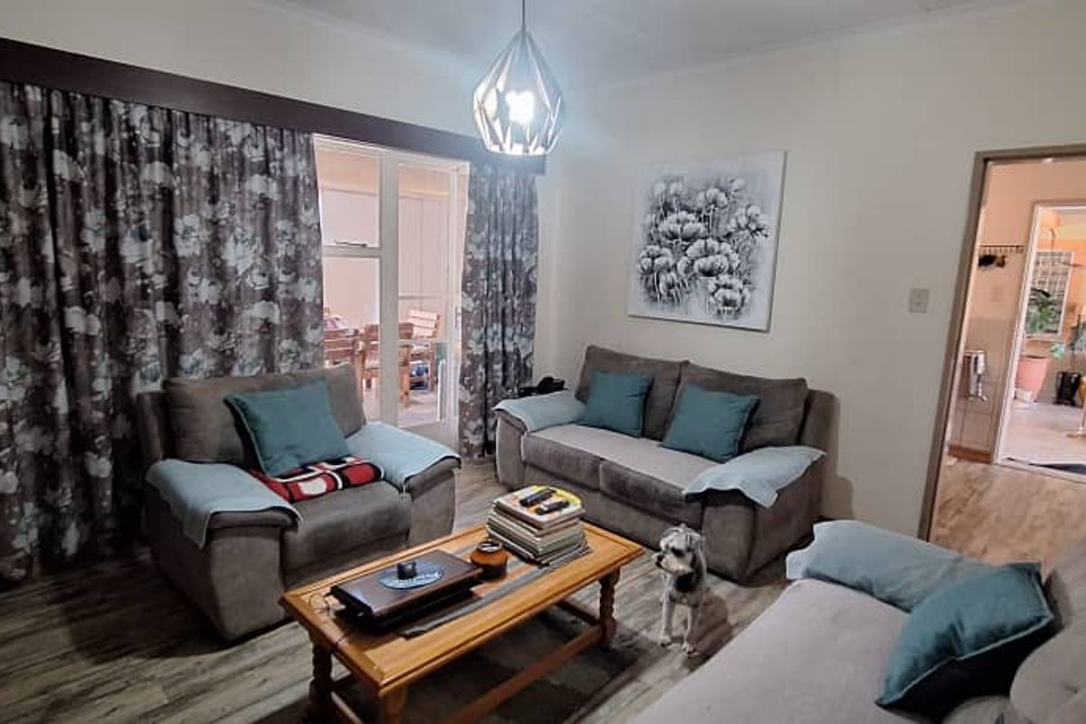 A comfortable living room featuring laminate flooring, a central pendant light, and a sliding glass door providing access to the outdoor patio area.