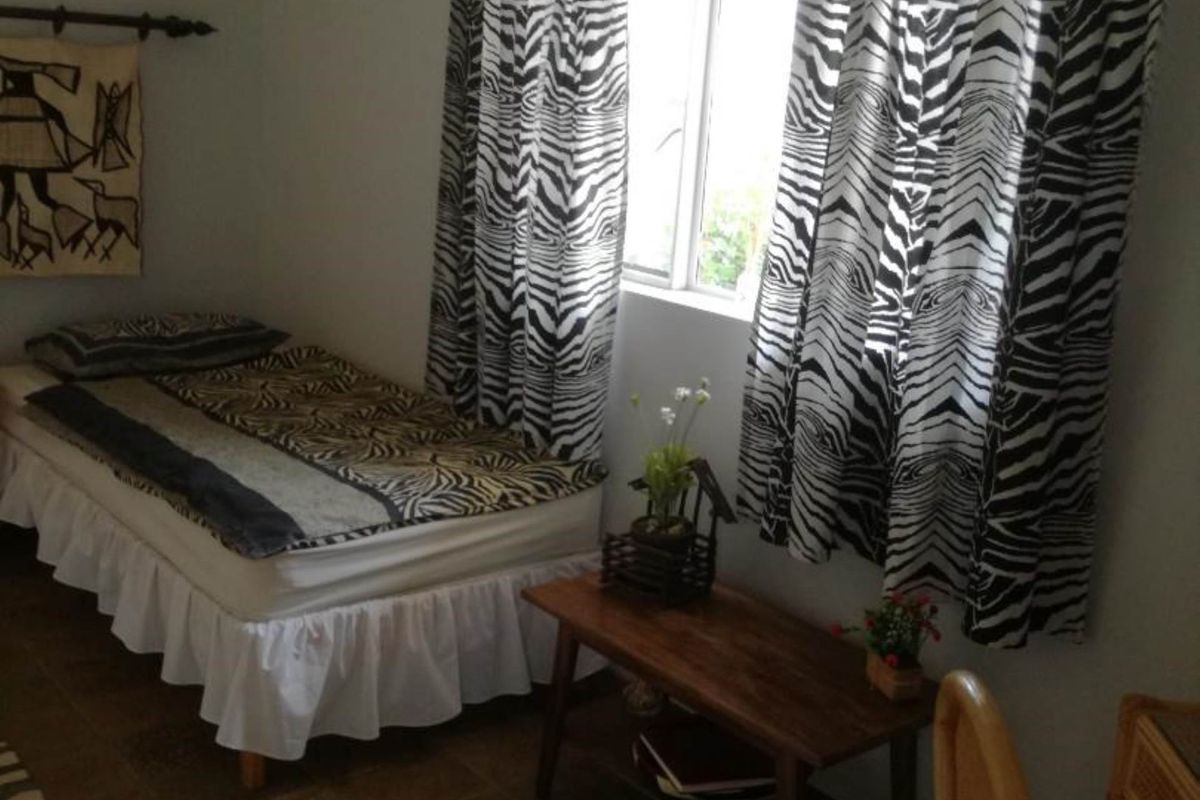 A bedroom featuring tiled flooring and a window with a wooden pelmet.