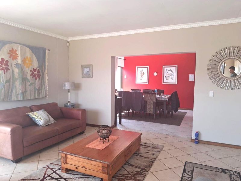 Open-plan living and dining area featuring neutral wall tones, ceramic floor tiles, and decorative ceiling cornicing, providing a versatile space for family living.