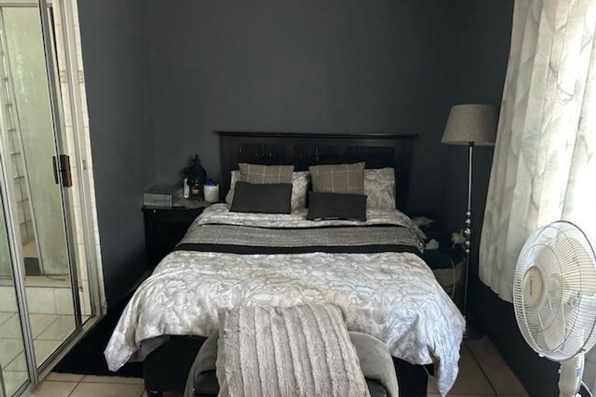 A bedroom featuring tiled flooring and an en-suite bathroom with a glass-enclosed shower.
