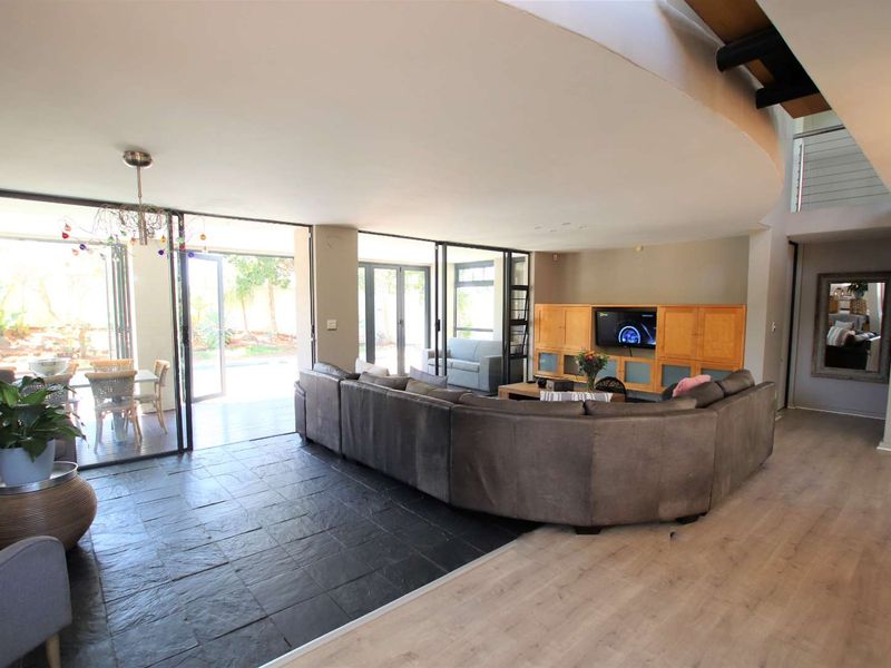 Spacious open-plan living area featuring a mix of slate and laminate flooring, large bi-fold doors opening to the patio, and built-in media cabinetry.