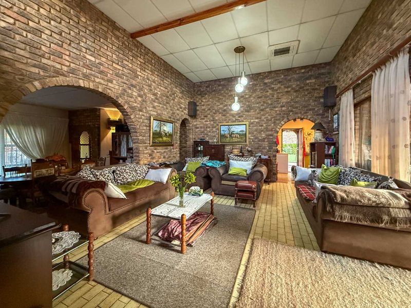 Spacious living room featuring rustic exposed brick walls, arched architectural details, and a high ceiling with exposed timber beams.