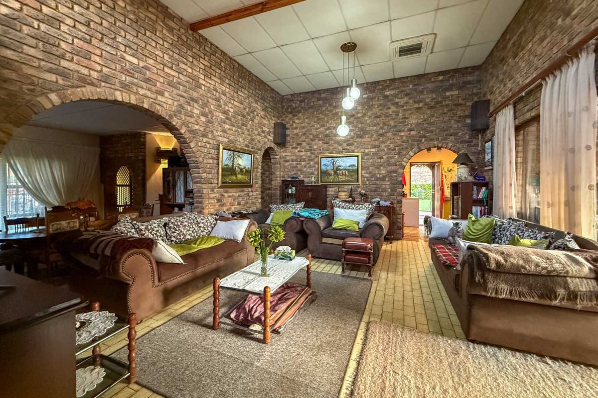 Spacious living room featuring rustic exposed brick walls, arched architectural details, and a high ceiling with exposed timber beams.