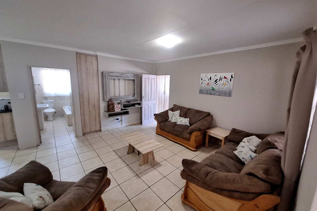 Open-plan living area featuring ceramic floor tiles, neutral wall finishes, and direct access to an adjoining bathroom.