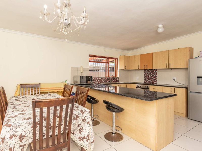 Open-plan kitchen and dining area featuring granite countertops, ample built-in cabinetry, and tiled flooring, creating a functional space for cooking and casual dining.
