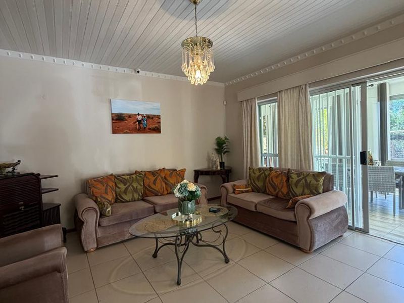 Spacious living room featuring tiled flooring, a classic beaded timber ceiling, and large sliding glass doors that provide access to the outdoor patio area.