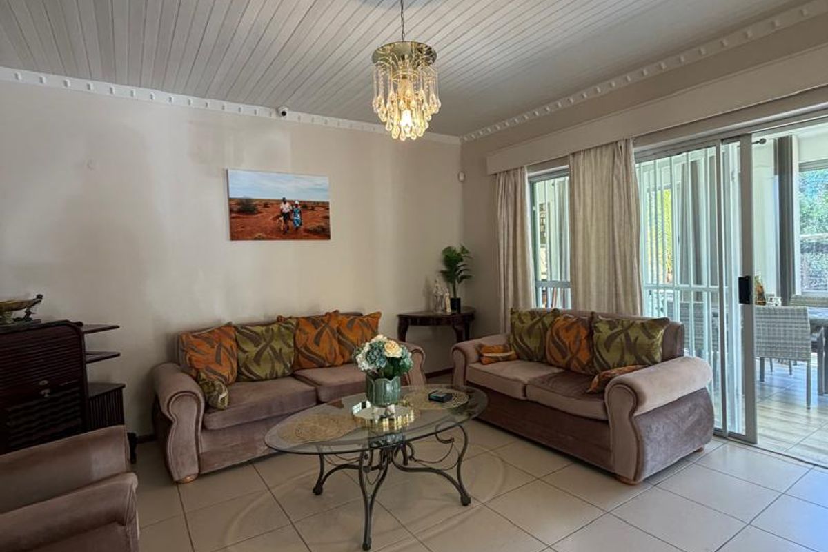 Spacious living room featuring tiled flooring, a classic beaded timber ceiling, and large sliding glass doors that provide access to the outdoor patio area.