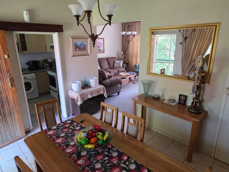 Open-plan dining and living area featuring tiled flooring, built-in storage, and an archway leading to the kitchen and lounge space.