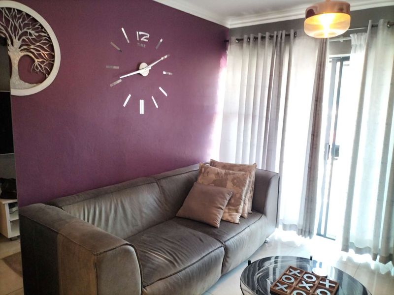 A living room featuring a feature wall, tiled flooring, and a sliding glass door providing access to the exterior.