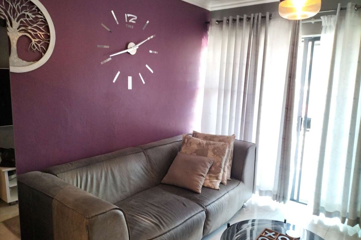 A living room featuring a feature wall, tiled flooring, and a sliding glass door providing access to the exterior.
