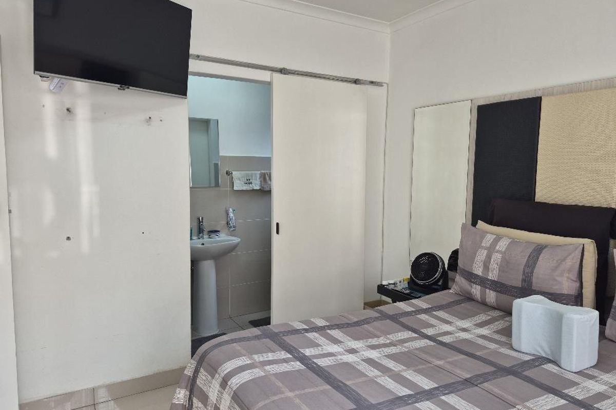 Bedroom featuring a sliding door leading to an en-suite bathroom with a pedestal basin and tiled flooring.