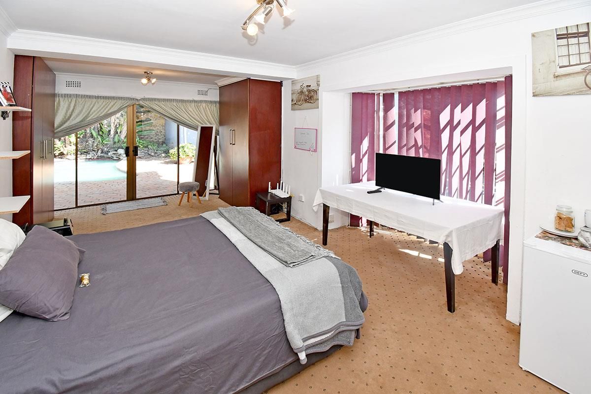 Spacious bedroom featuring built-in cabinetry, carpeted flooring, and sliding glass doors providing direct access to the outdoor pool area.