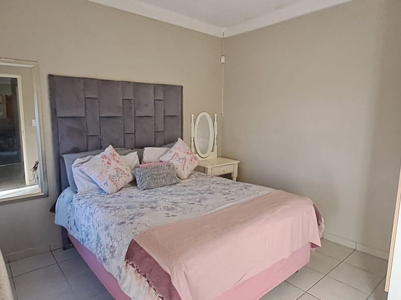 A functional bedroom featuring tiled flooring, a built-in wardrobe, and coved ceiling detailing.