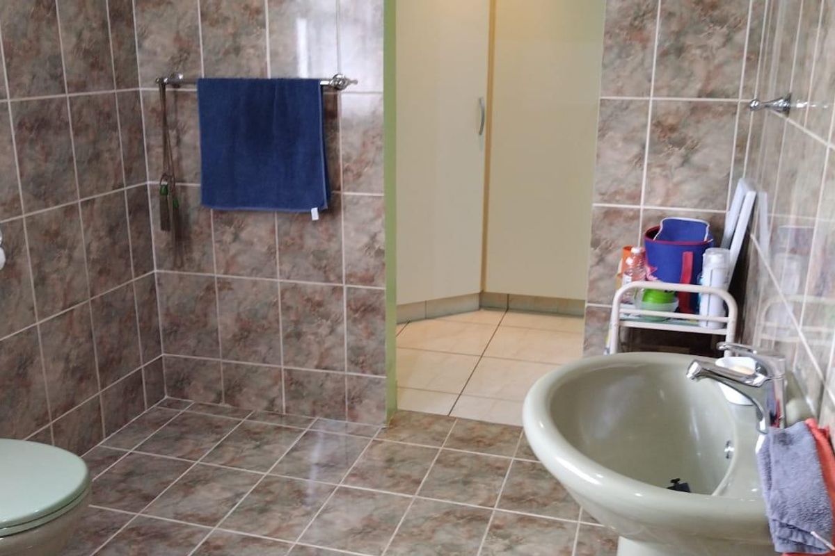 A functional bathroom featuring tiled walls and flooring, a pedestal basin, and a standard toilet suite.