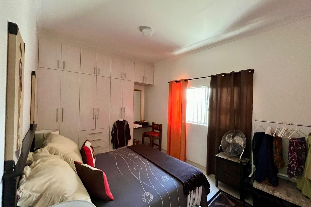 A bedroom featuring extensive built-in floor-to-ceiling cabinetry with integrated vanity space and a window with security bars.