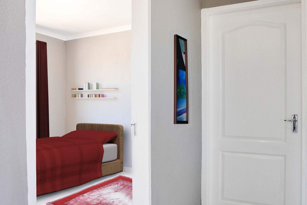 A view from a hallway into a bedroom featuring neutral walls, built-in shelving, and a classic internal door.