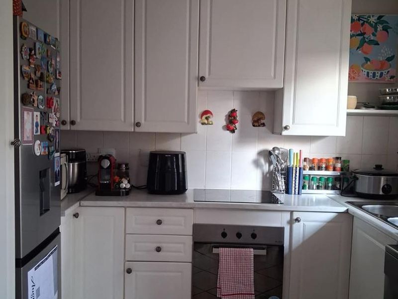 A functional kitchen featuring white cabinetry, a built-in oven with electric hob, tiled backsplash, and tiled flooring.