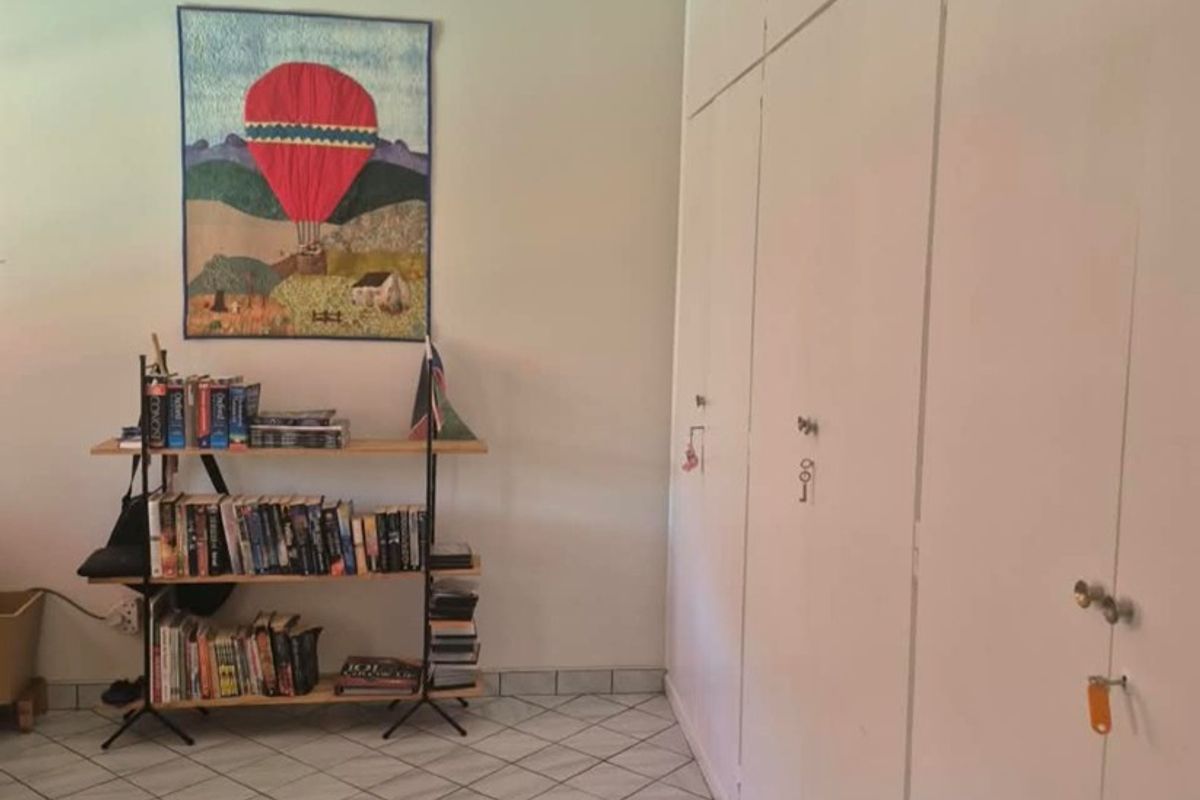 A bedroom featuring tiled flooring and extensive floor-to-ceiling built-in cupboards providing ample storage space.