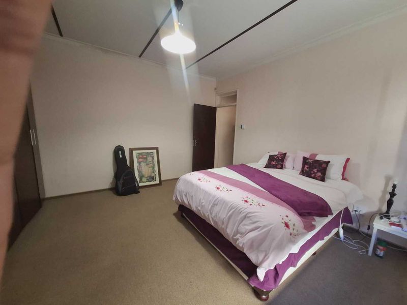 A spacious bedroom featuring neutral walls, carpeted flooring, and a built-in wardrobe, offering a functional and comfortable living space.