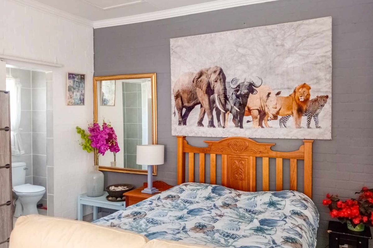 A bedroom featuring a grey accent wall, crown molding, and direct access to an en-suite bathroom.