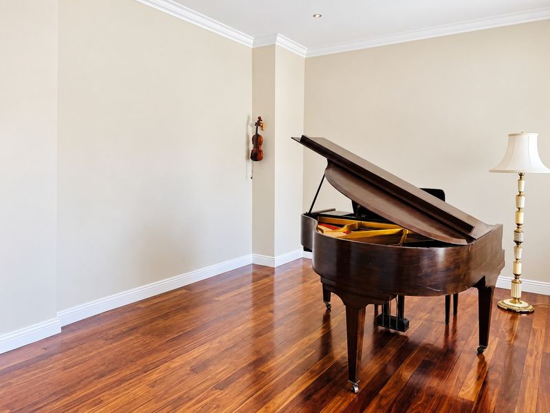 A bright living area featuring polished hardwood flooring, elegant crown molding, and recessed ceiling lighting, providing a clean and neutral space.