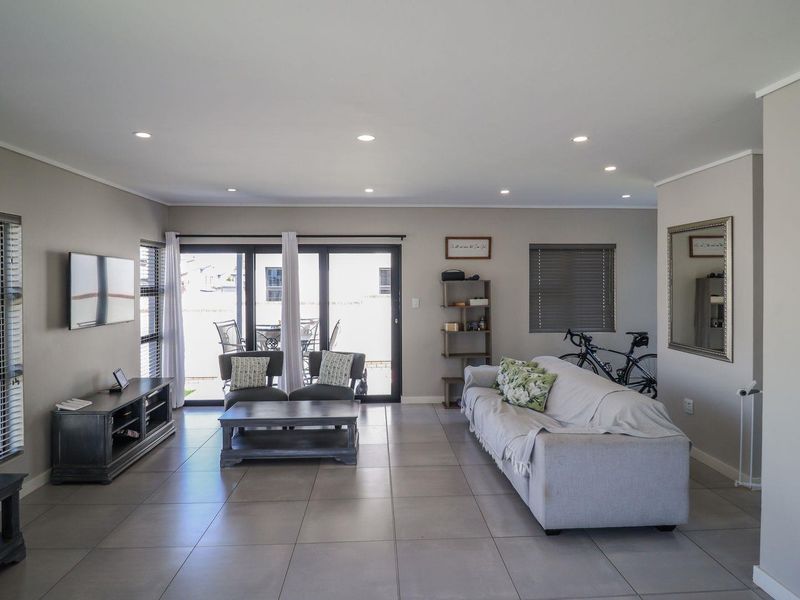 Spacious living room featuring neutral tiled flooring, recessed downlighting, and large sliding glass doors providing access to the outdoor patio area.