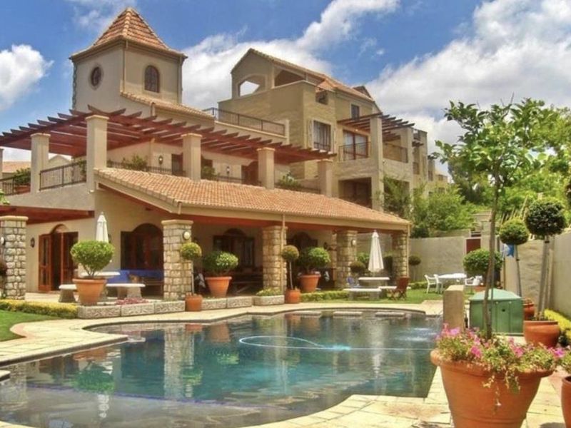 A well-maintained outdoor pool area featuring stone-clad pillars, a timber pergola, and a spacious terrace, perfect for relaxation and outdoor entertainment.