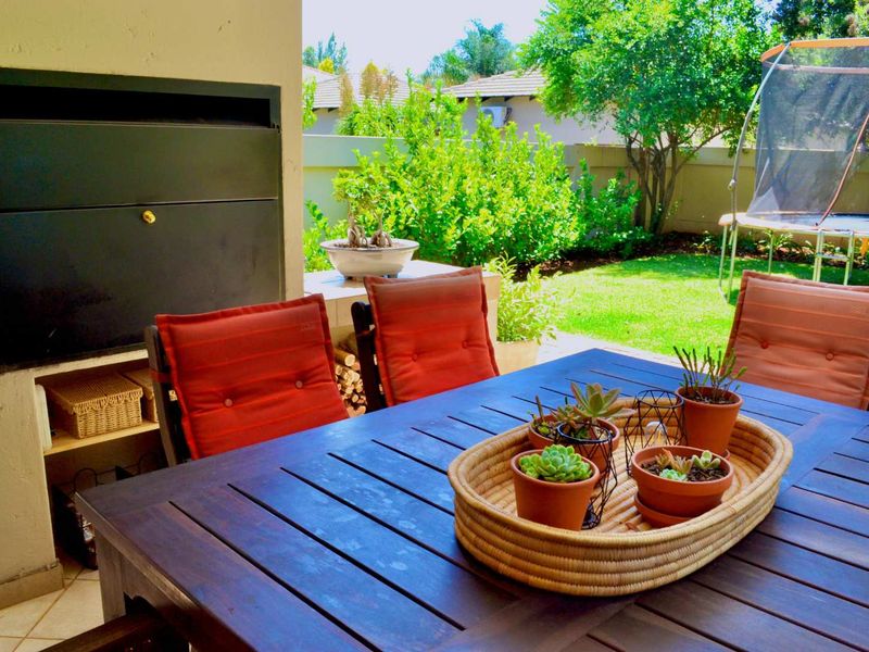 Covered patio area featuring a built-in braai and tiled flooring, overlooking a private garden space.
