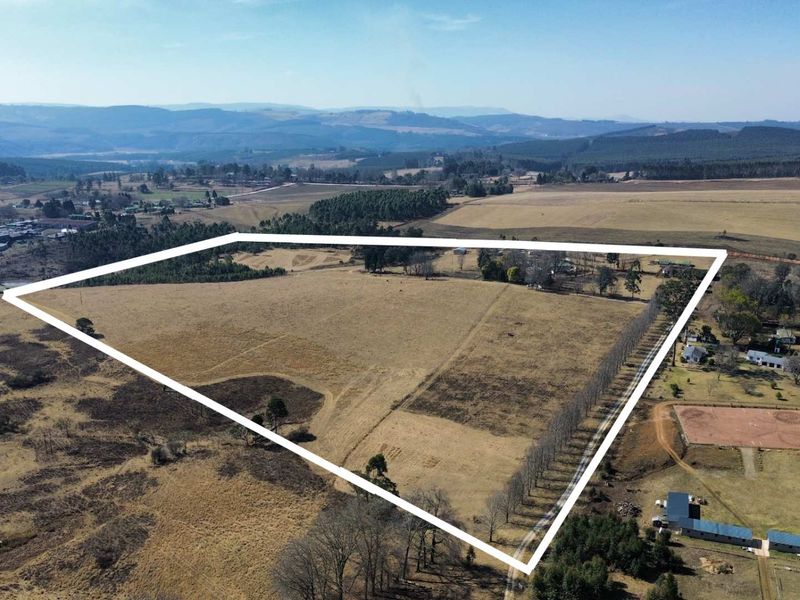An aerial view of a large farm property featuring expansive open fields, established tree lines, and clear boundary demarcations within a rural landscape.