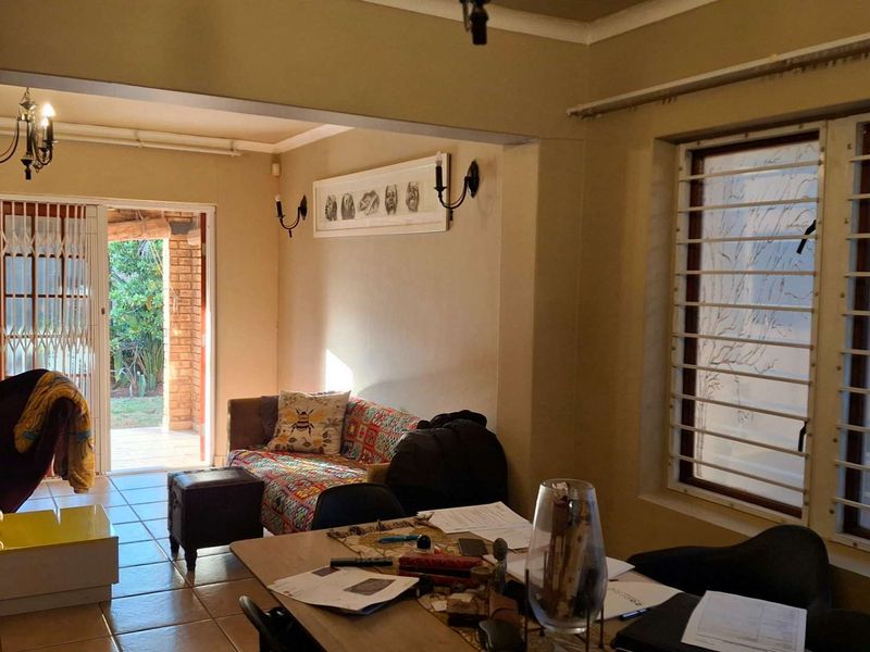 Open plan living and dining area featuring tiled flooring, security bars on windows, and a sliding door providing access to the outdoor patio.
