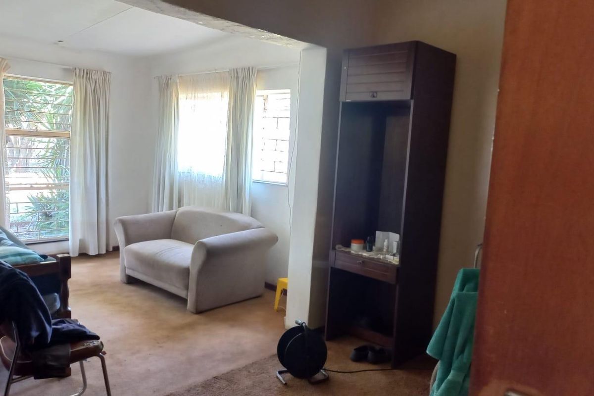 A bedroom featuring carpeted flooring, large windows with curtains, and a built-in storage unit.