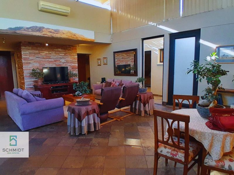 Spacious open-plan living and dining area featuring high ceilings, a stone feature wall, and tiled flooring throughout.