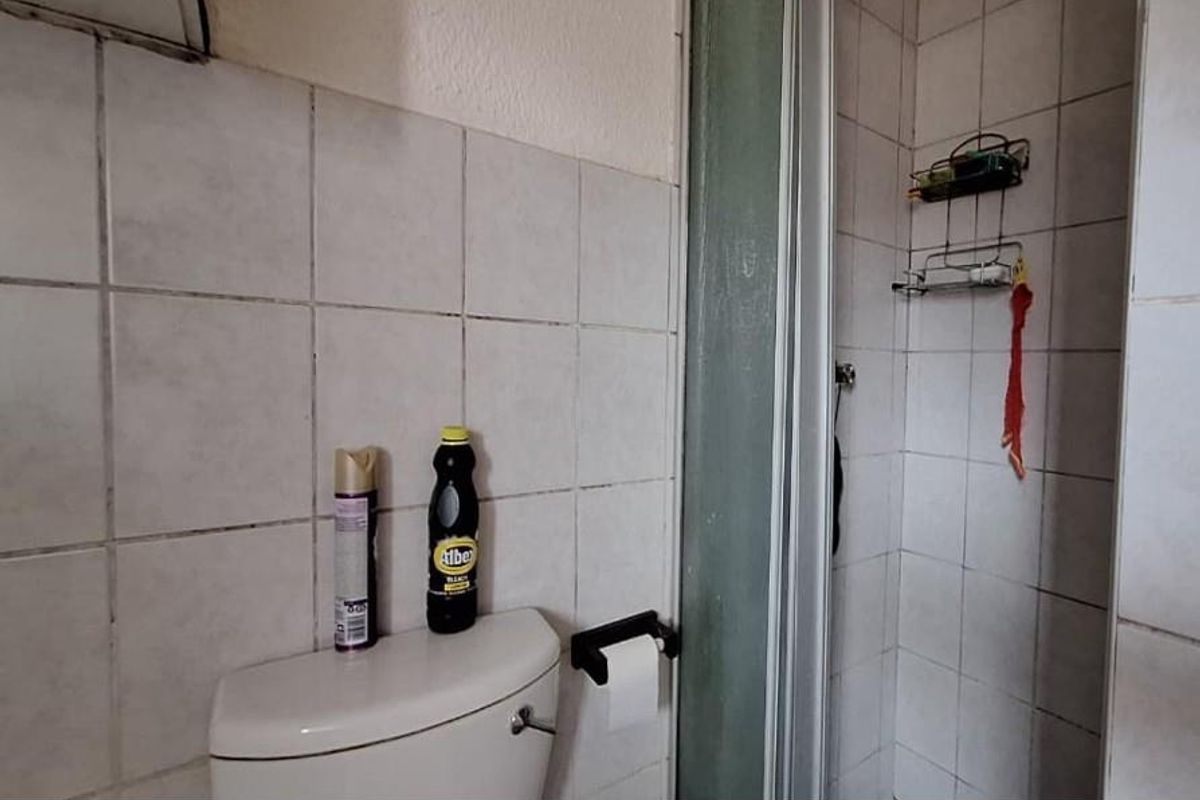 A compact bathroom featuring a standard toilet and a tiled shower enclosure with a sliding glass door.