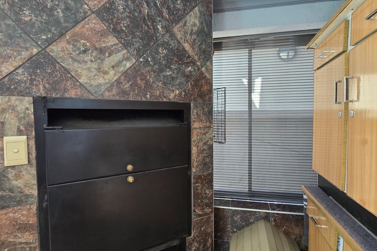 A living area featuring a built-in fireplace with decorative tiled surround, integrated cabinetry, and window blinds.