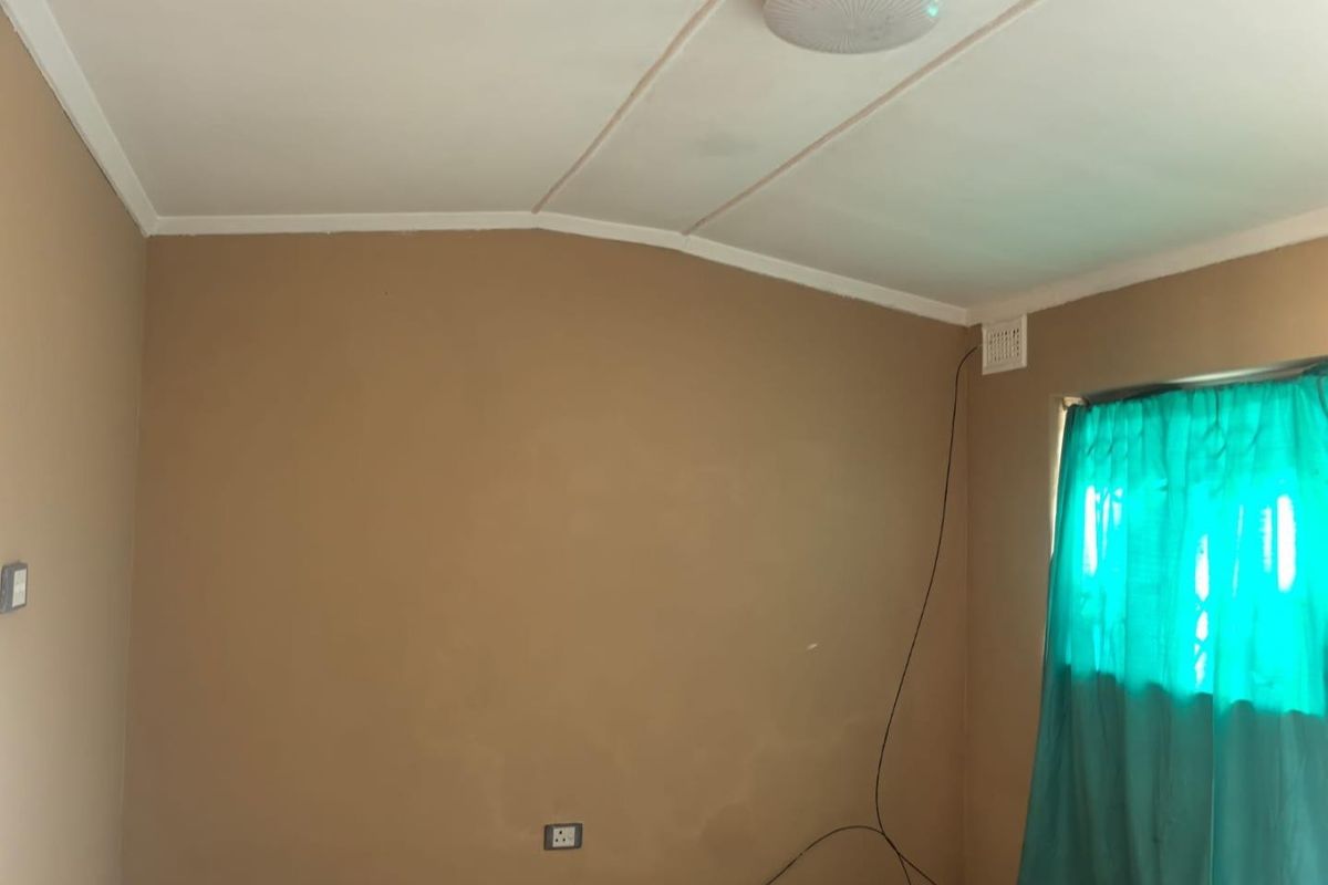 An empty bedroom featuring neutral wall paint, a ceiling light fixture, and a ventilation grille, requiring minor cosmetic updates.