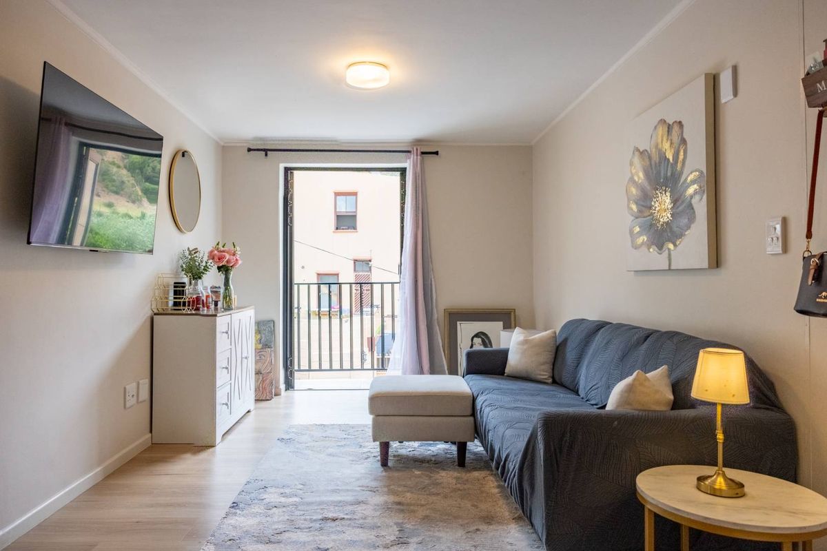 A well-lit living room featuring laminate flooring and direct access to a private balcony, creating a bright and functional living space.