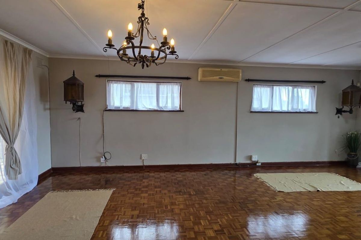 Spacious living room featuring polished parquet flooring, a decorative wrought iron chandelier, and dual sliding glass doors providing access to the exterior.