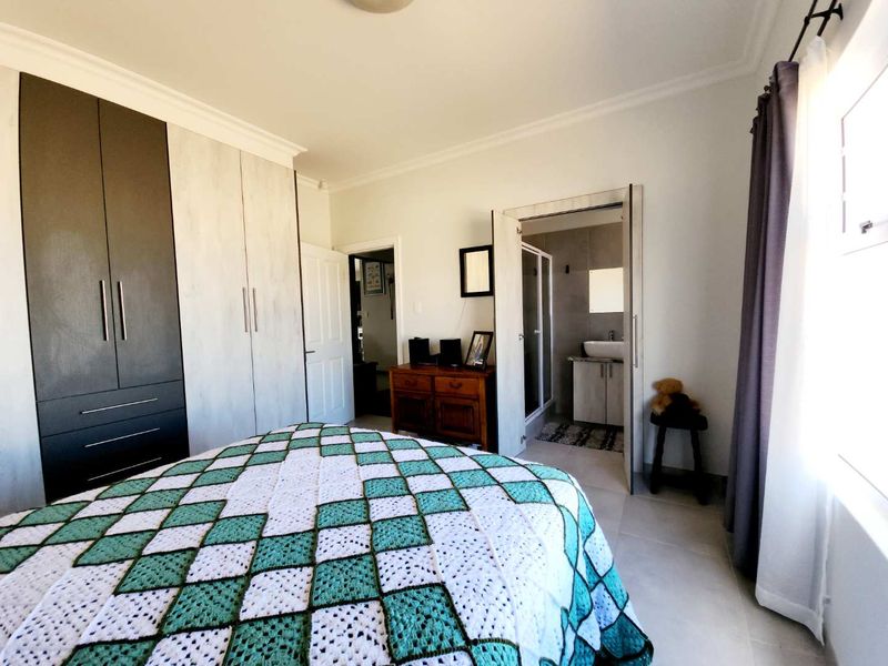A well-maintained bedroom featuring built-in cupboards, tiled flooring, and direct access to an en-suite bathroom.