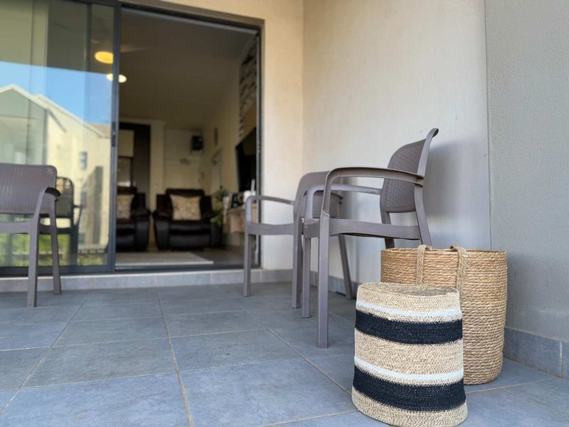A covered patio area featuring tiled flooring and a large sliding glass door providing access to the interior living space.