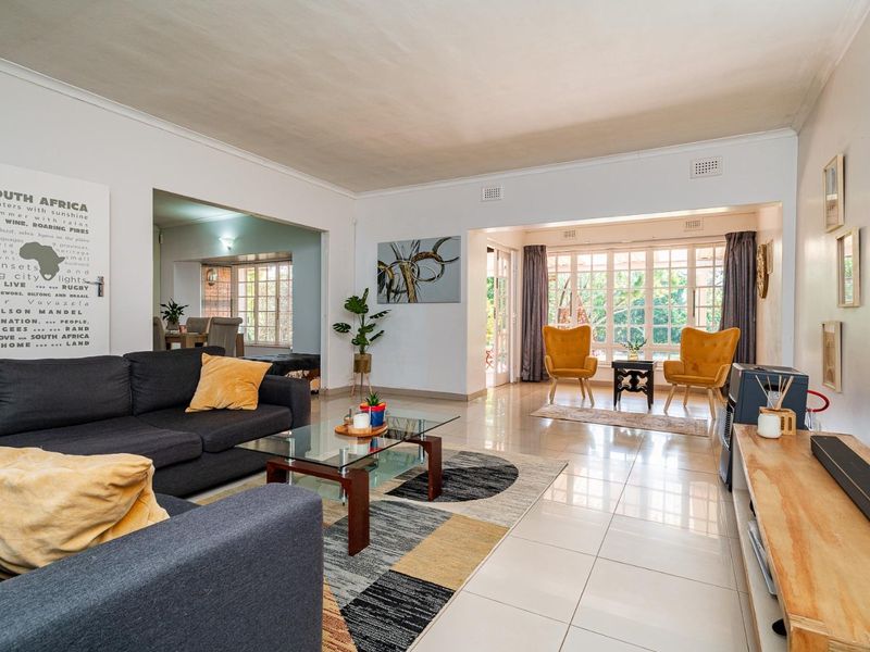 Spacious open-plan living area featuring bright tiled flooring, large windows, and seamless flow to the outdoor patio area.
