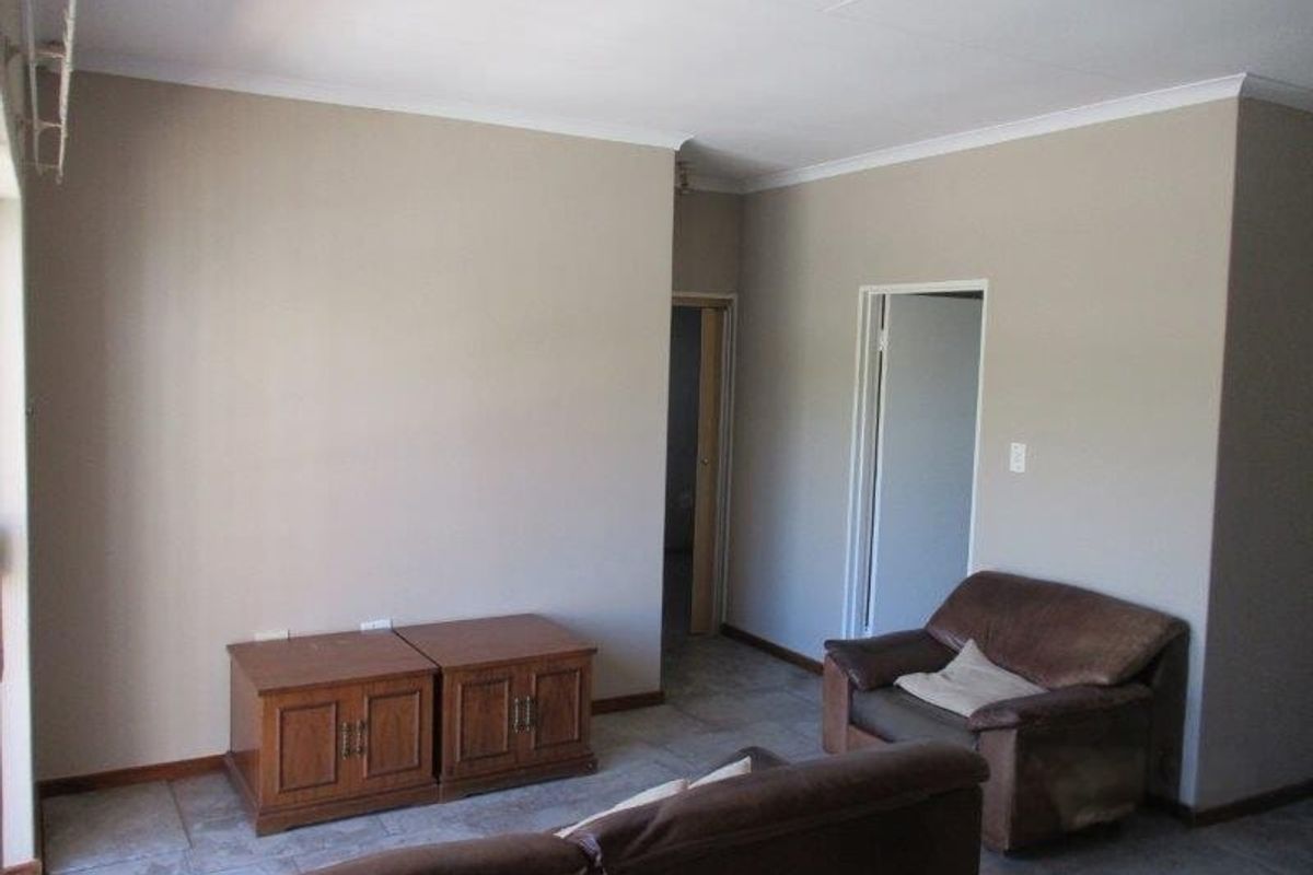 A living room area featuring neutral wall tones, tiled flooring, and access to adjacent rooms through standard doorways.