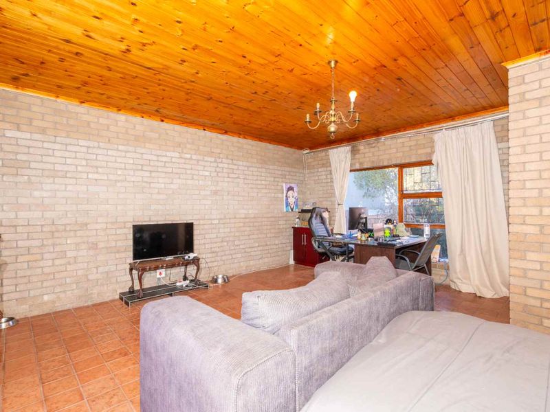 Spacious living area featuring exposed brick walls, a warm timber tongue and groove ceiling, and terracotta floor tiles.