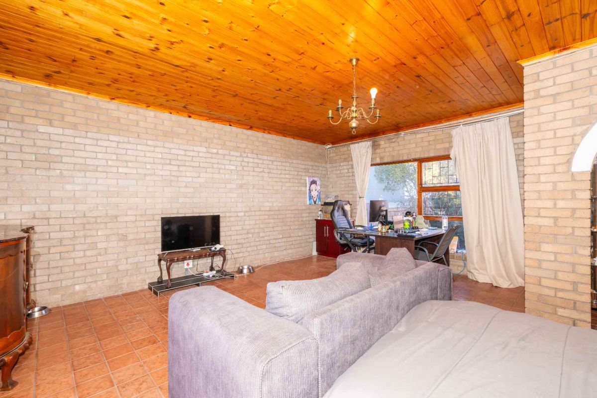 Spacious living area featuring exposed brick walls, a warm timber tongue and groove ceiling, and terracotta floor tiles.