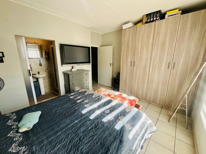 A bedroom featuring built-in wardrobes, tiled flooring, and direct access to an en-suite bathroom.