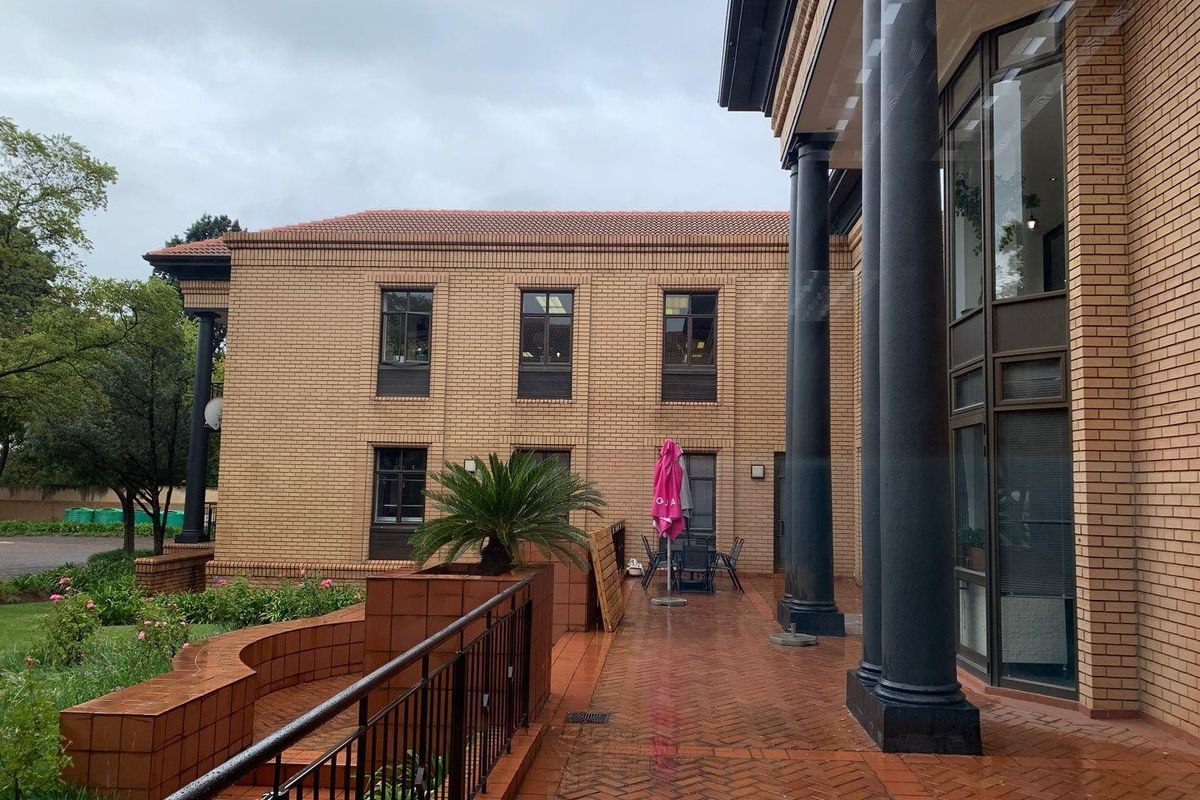 A view of the office building exterior featuring a paved patio area, brick facade, and decorative columns.