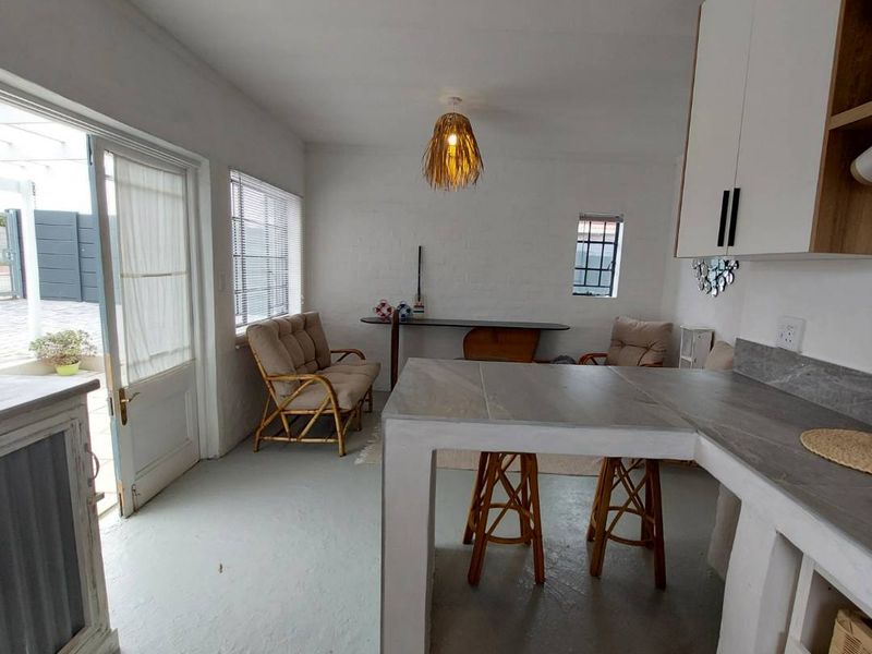Open-plan kitchen and living area featuring built-in cabinetry, a stone-look breakfast bar, and direct access to an outdoor patio space.